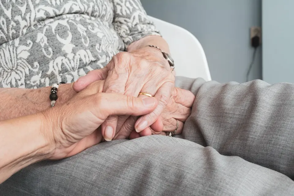 An older woman's hands held in a caregiver's hands