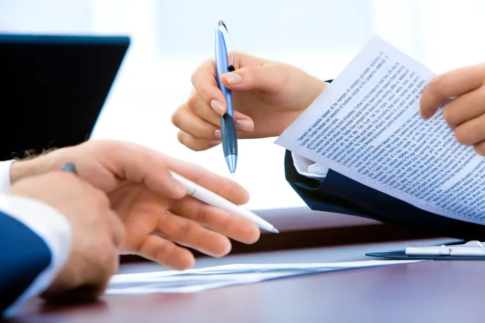 A person writing notes beside a laptop