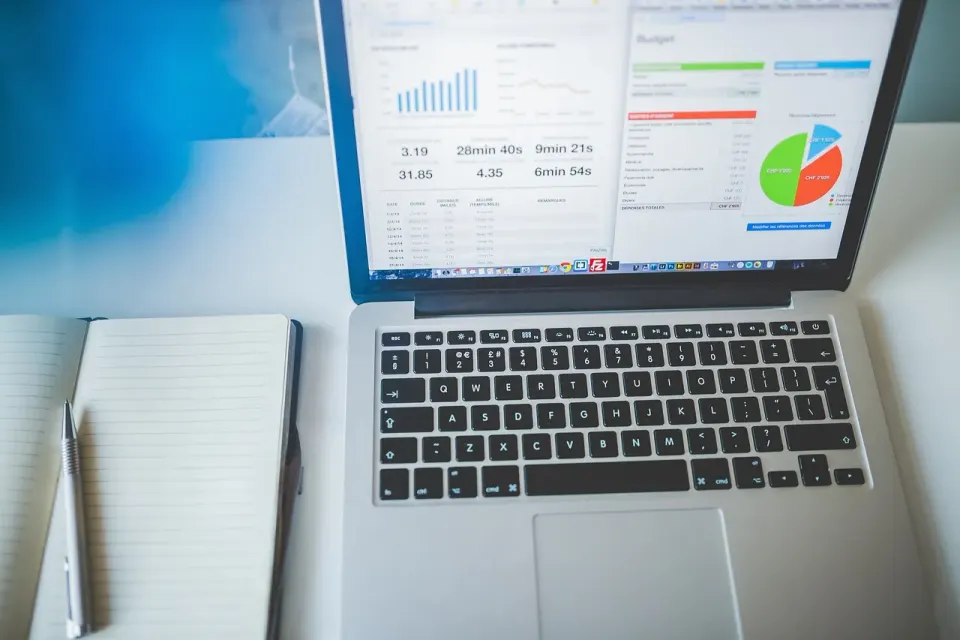 A laptop and notebook with charts used for budget planning